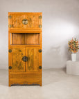 Tall elm and burlwood cabinet styled with a floral arrangement