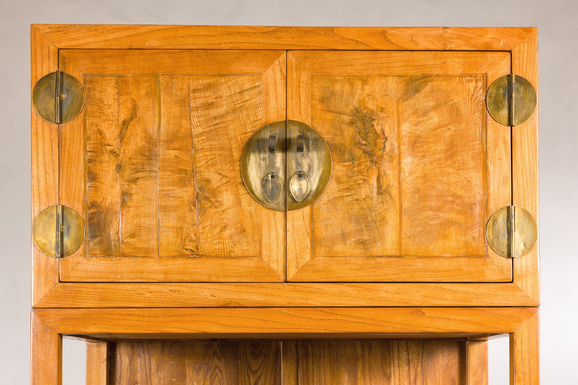 Close-up of upper burlwood doors with brass hinges and lock plate