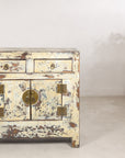 Small distressed cream cabinet displayed beside a floral arrangement