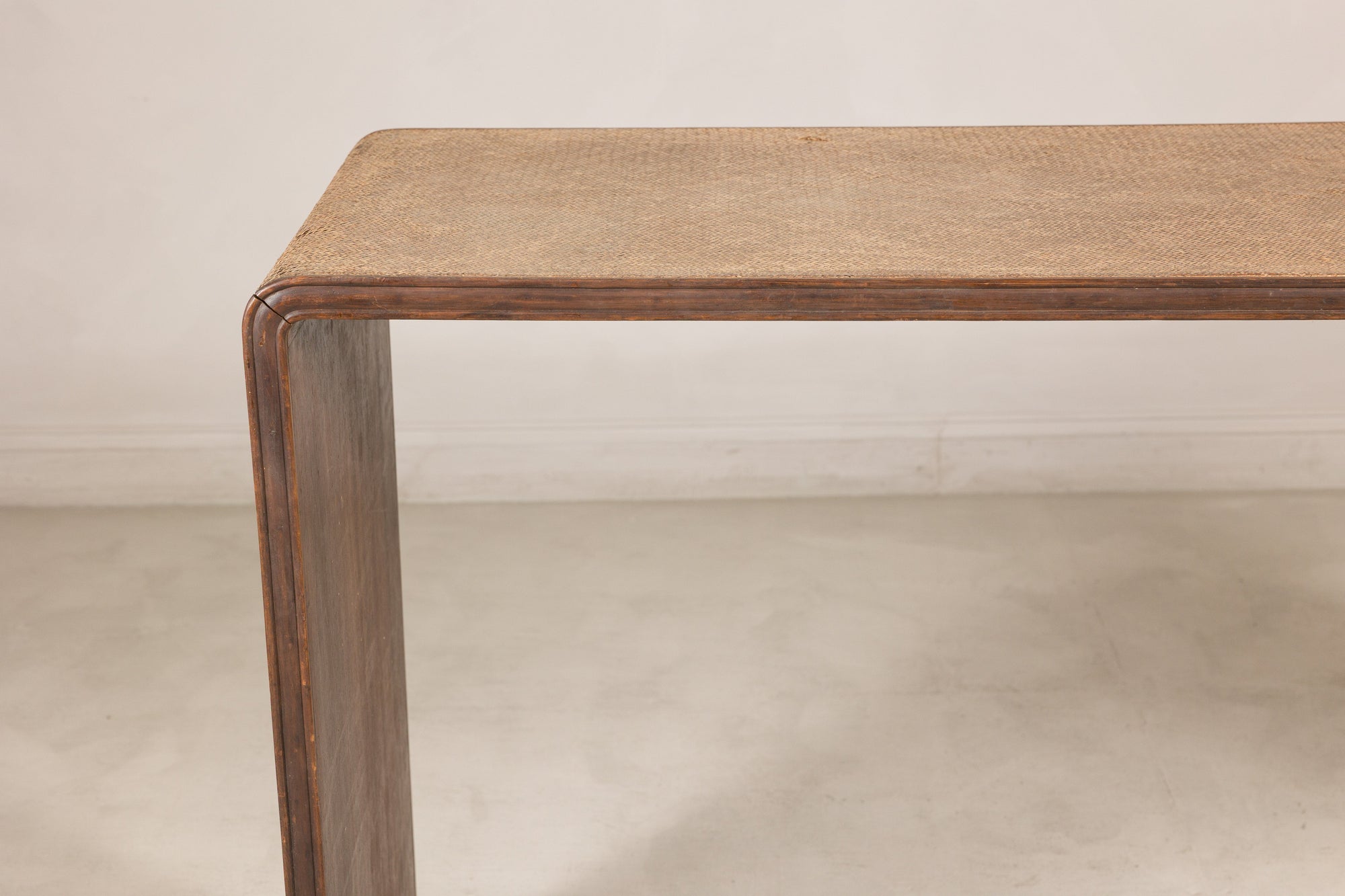 Close-up of the waterfall edge where the rattan top meets dark wood