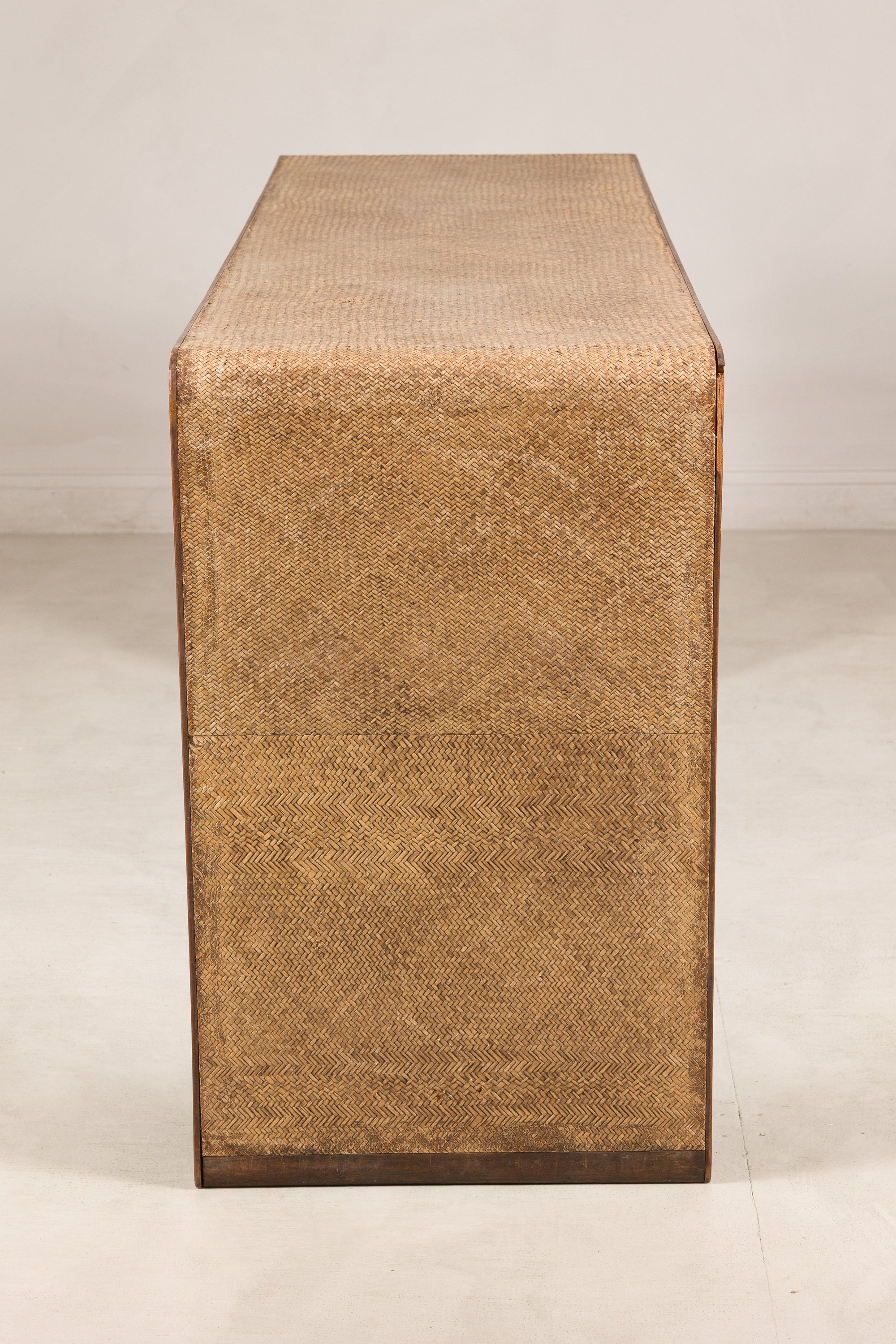 End view of the waterfall console showing woven rattan and dark wood trim