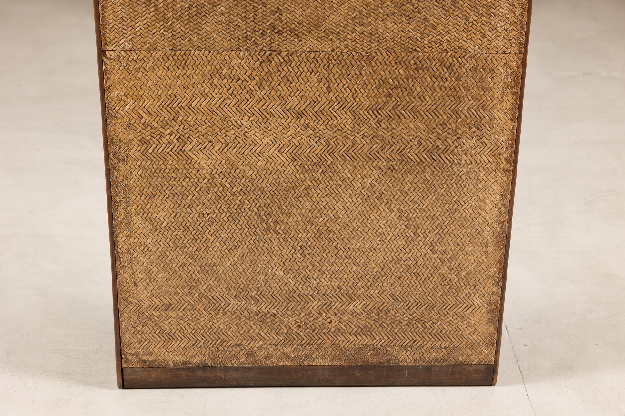 Close-up of a woven rattan end panel framed in dark wood