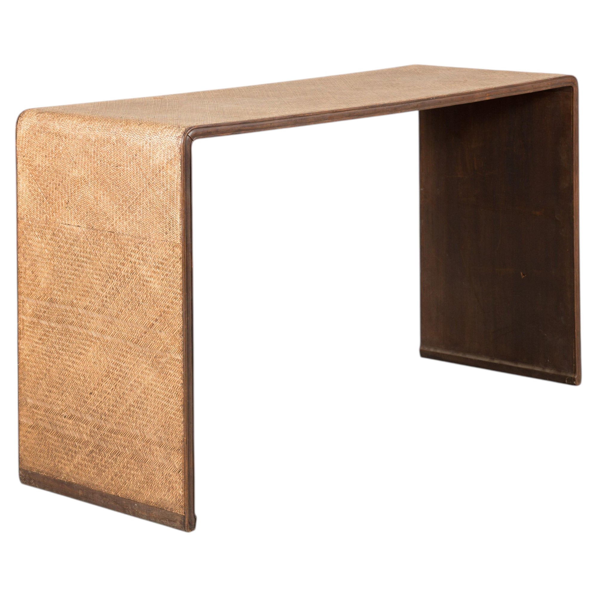Woven rattan and dark wood waterfall console table on a white background