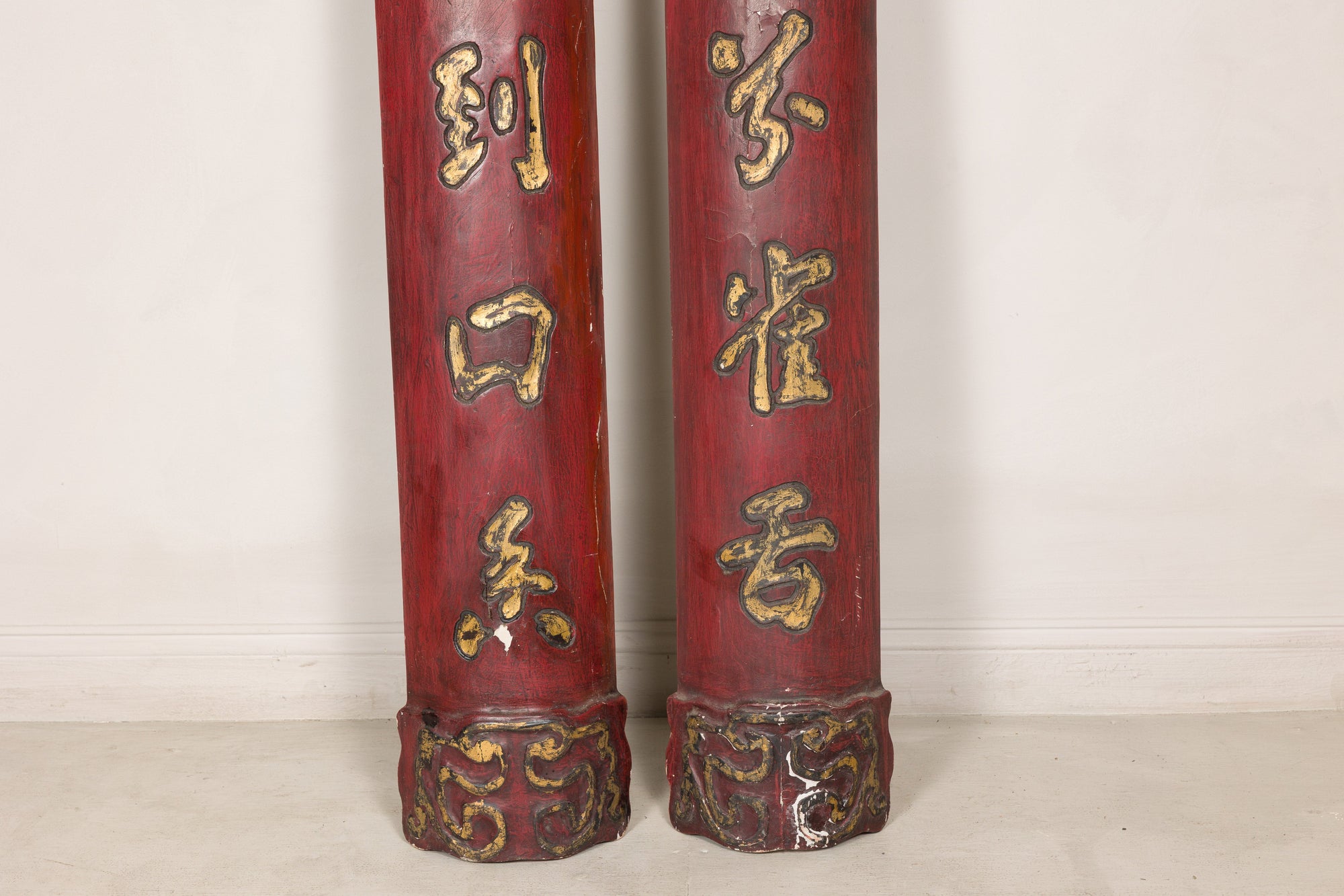Close-up of lower gilt characters and carved bases on red Chinese wood panels