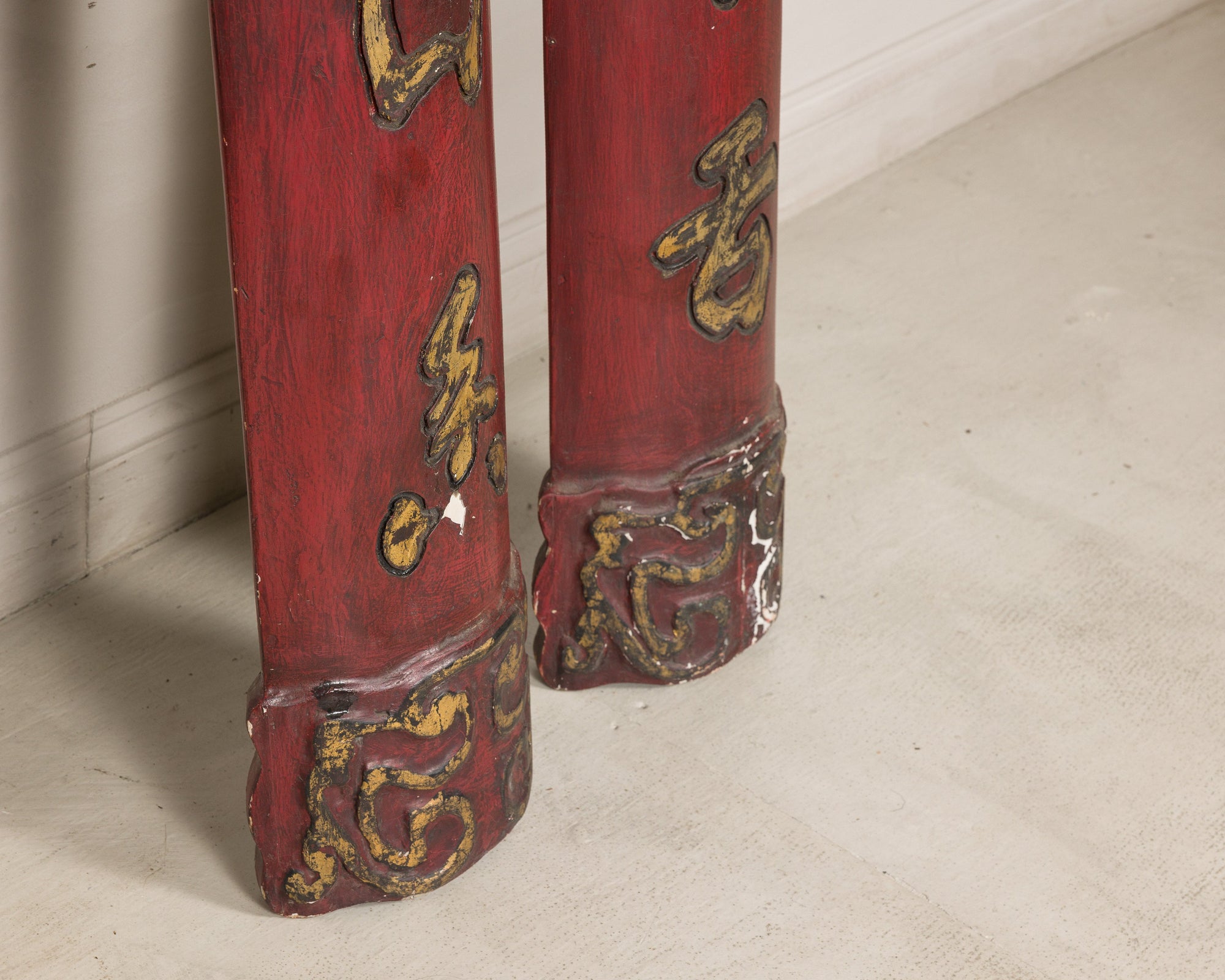 Close-up of carved lower ends with worn red and gilt finish on Chinese panels
