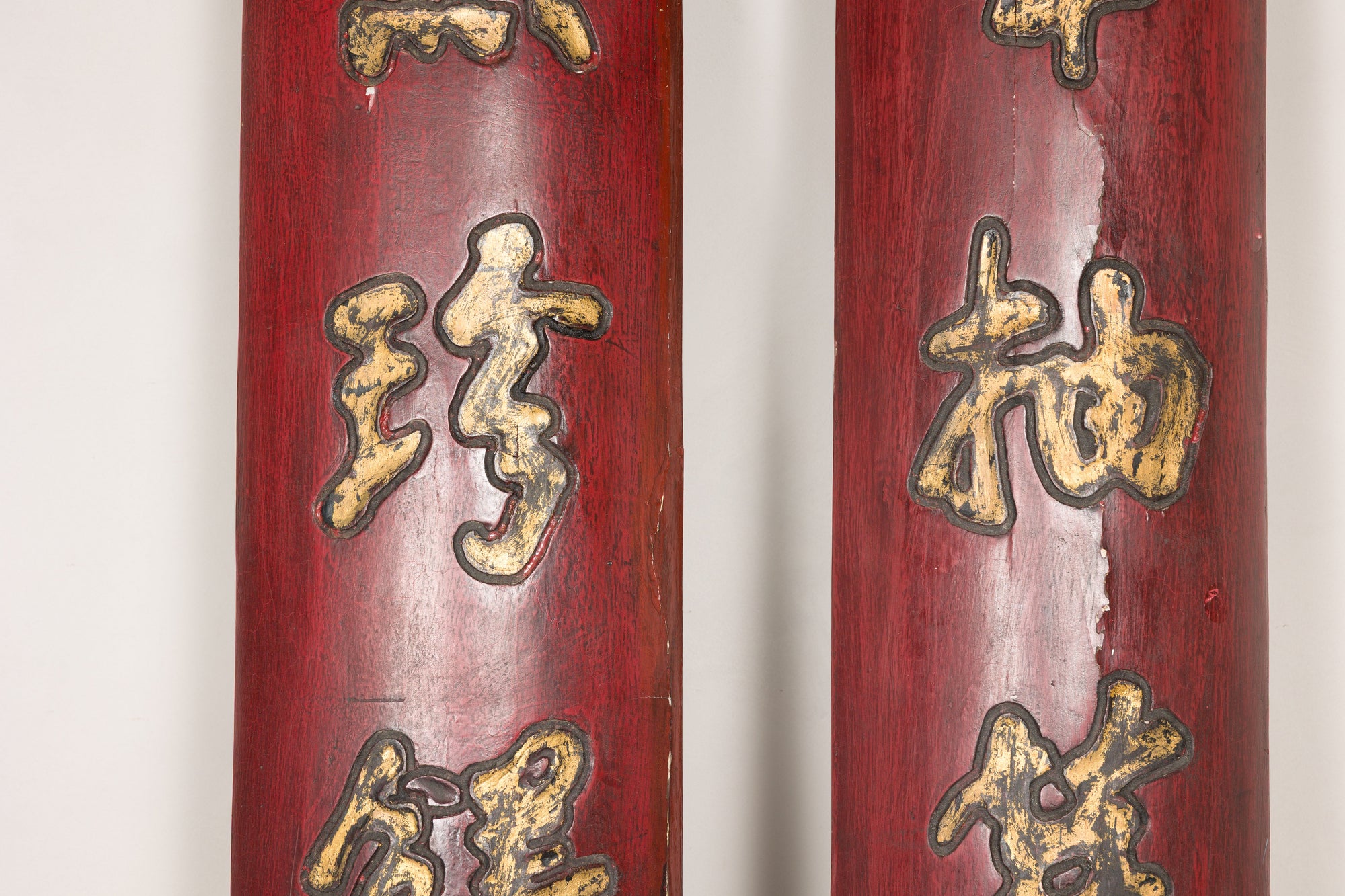 Close-up of raised gilt calligraphy and aged red lacquer on paired wood panels