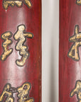 Close-up of raised gilt calligraphy and aged red lacquer on paired wood panels