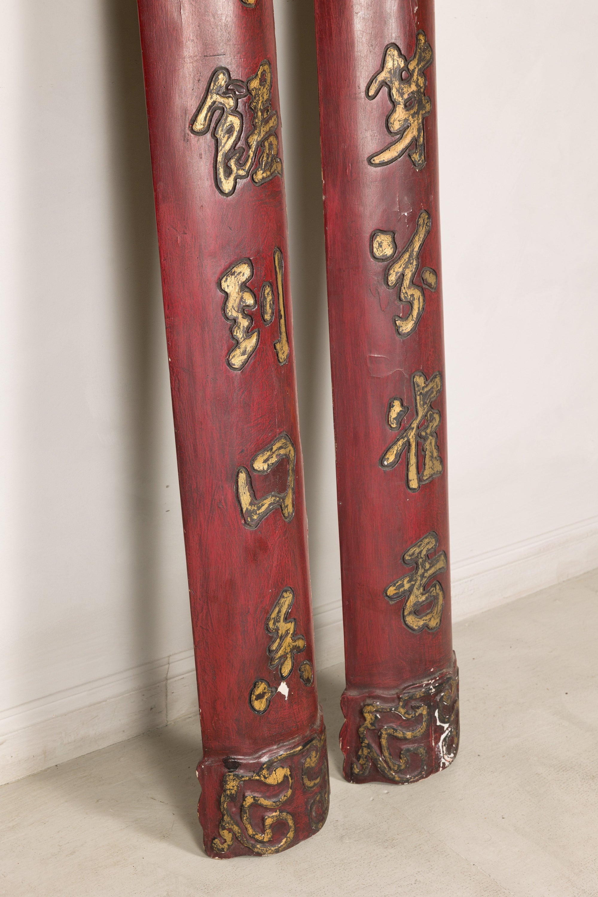Close-up of the lower sections of red wood panels with gilt calligraphy and carved ends