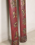 Close-up of the lower sections of red wood panels with gilt calligraphy and carved ends