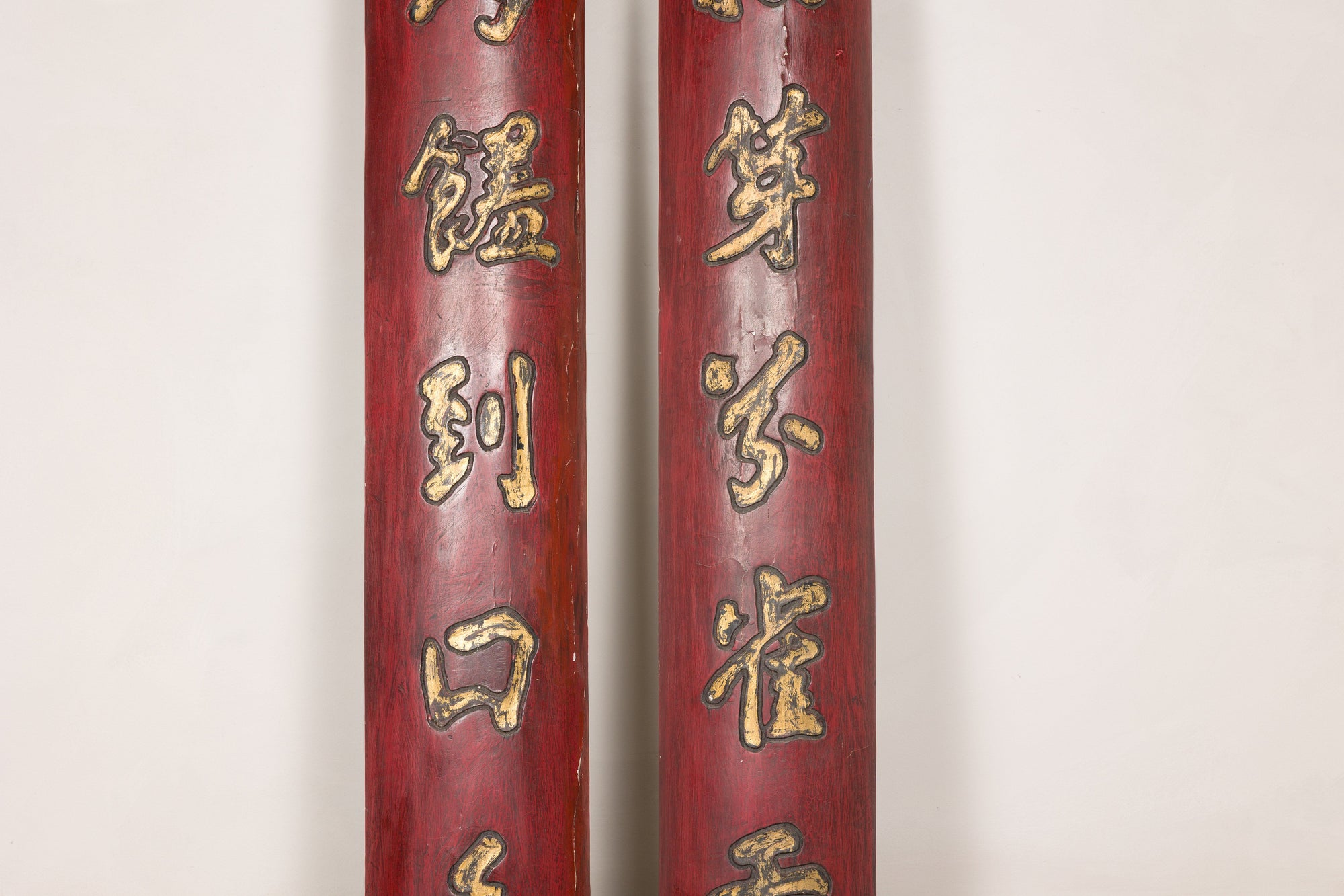 Close-up of raised gilt Chinese characters on the red wood panel surfaces