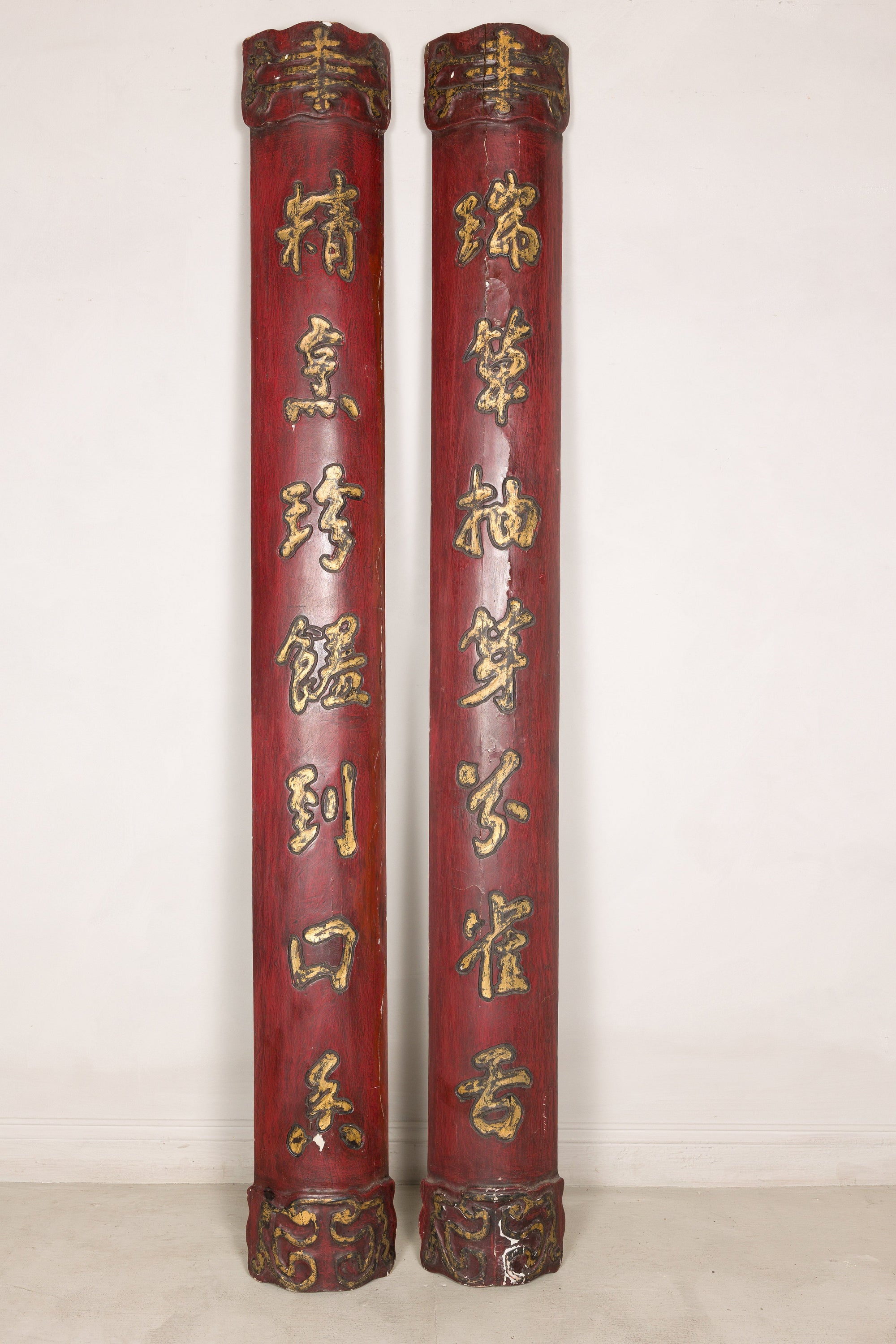 Side profile of paired red wood panels showing carved cylindrical forms