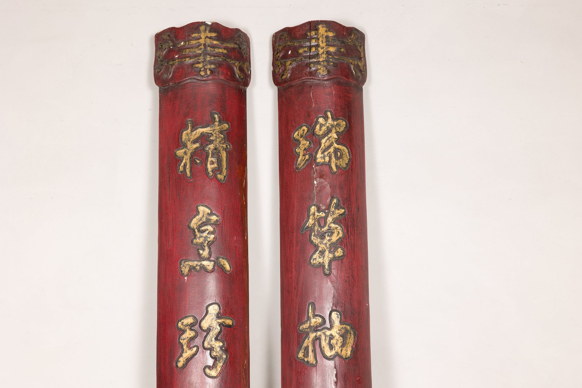 Close-up of carved upper ends and raised gilt characters on red wood panels