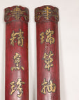 Close-up of carved upper ends and raised gilt characters on red wood panels