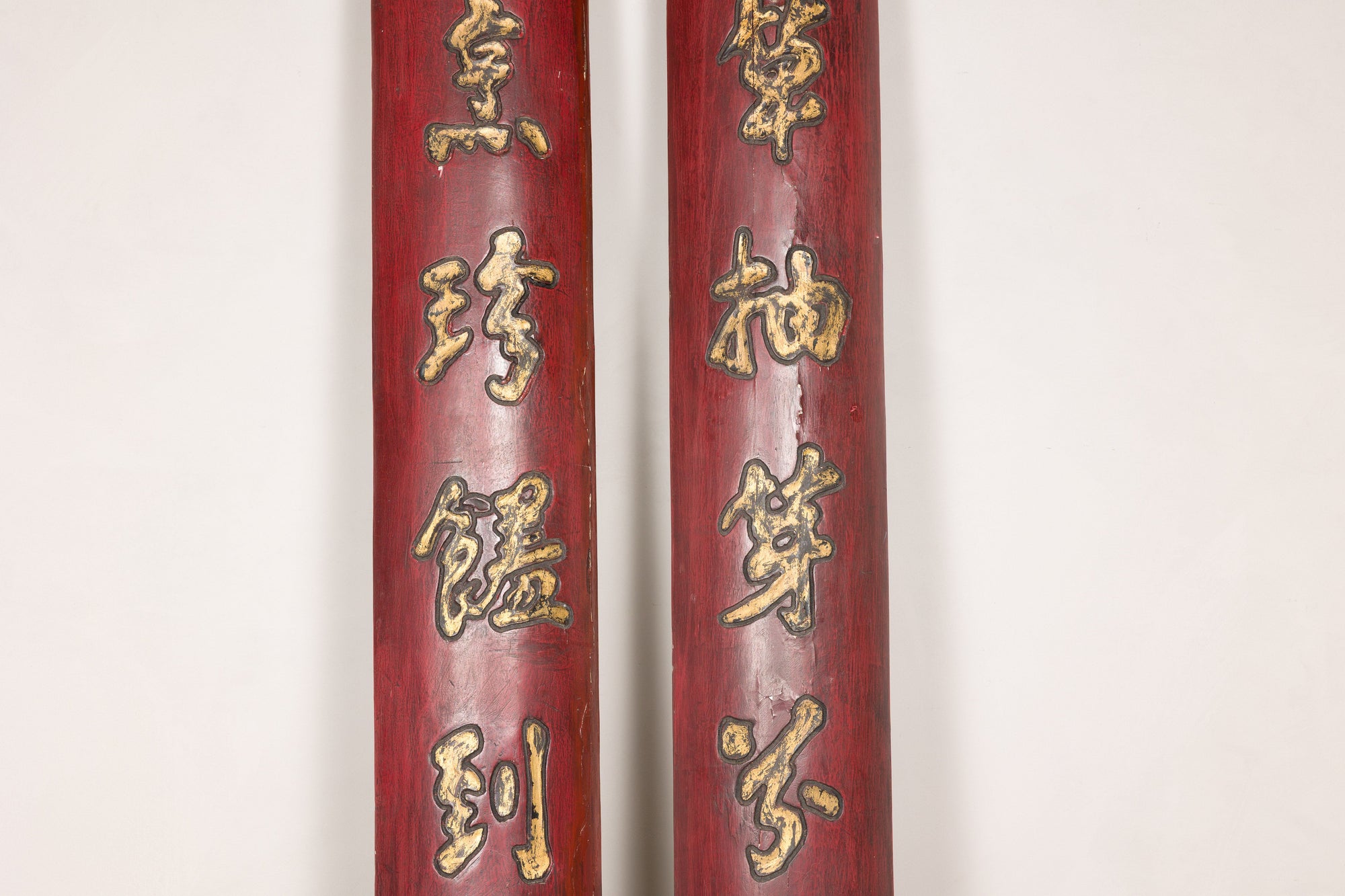 Upper detail of paired red calligraphy panels showing gilt finish and age cracks