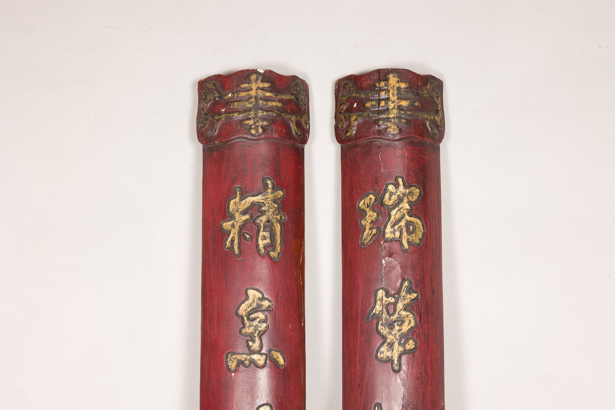 Close-up of shaped upper caps and gilt calligraphy on paired red wood panels