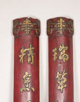Close-up of shaped upper caps and gilt calligraphy on paired red wood panels