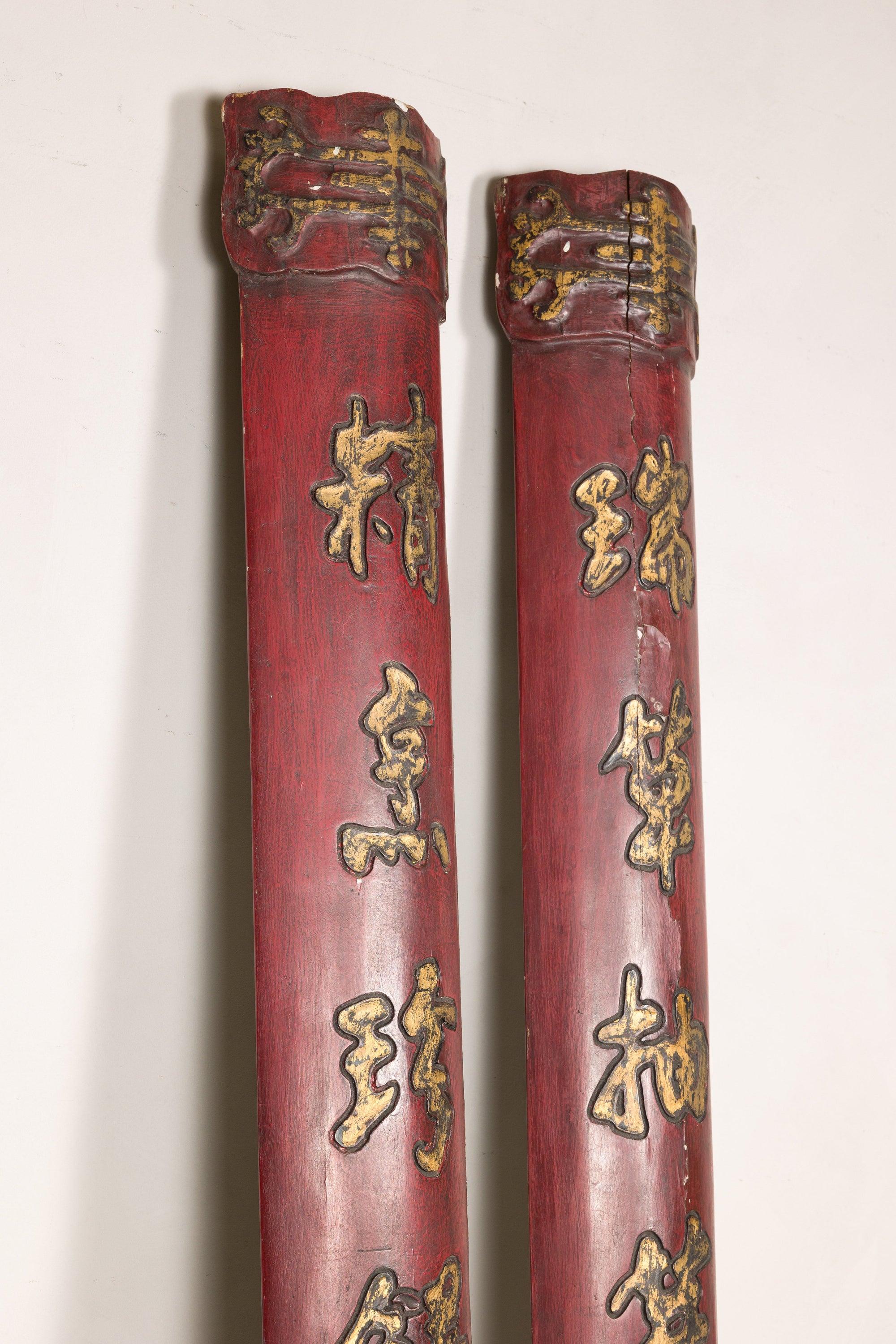 Close-up of the upper sections of red wood panels with raised gilt calligraphy