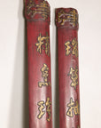 Close-up of the upper sections of red wood panels with raised gilt calligraphy