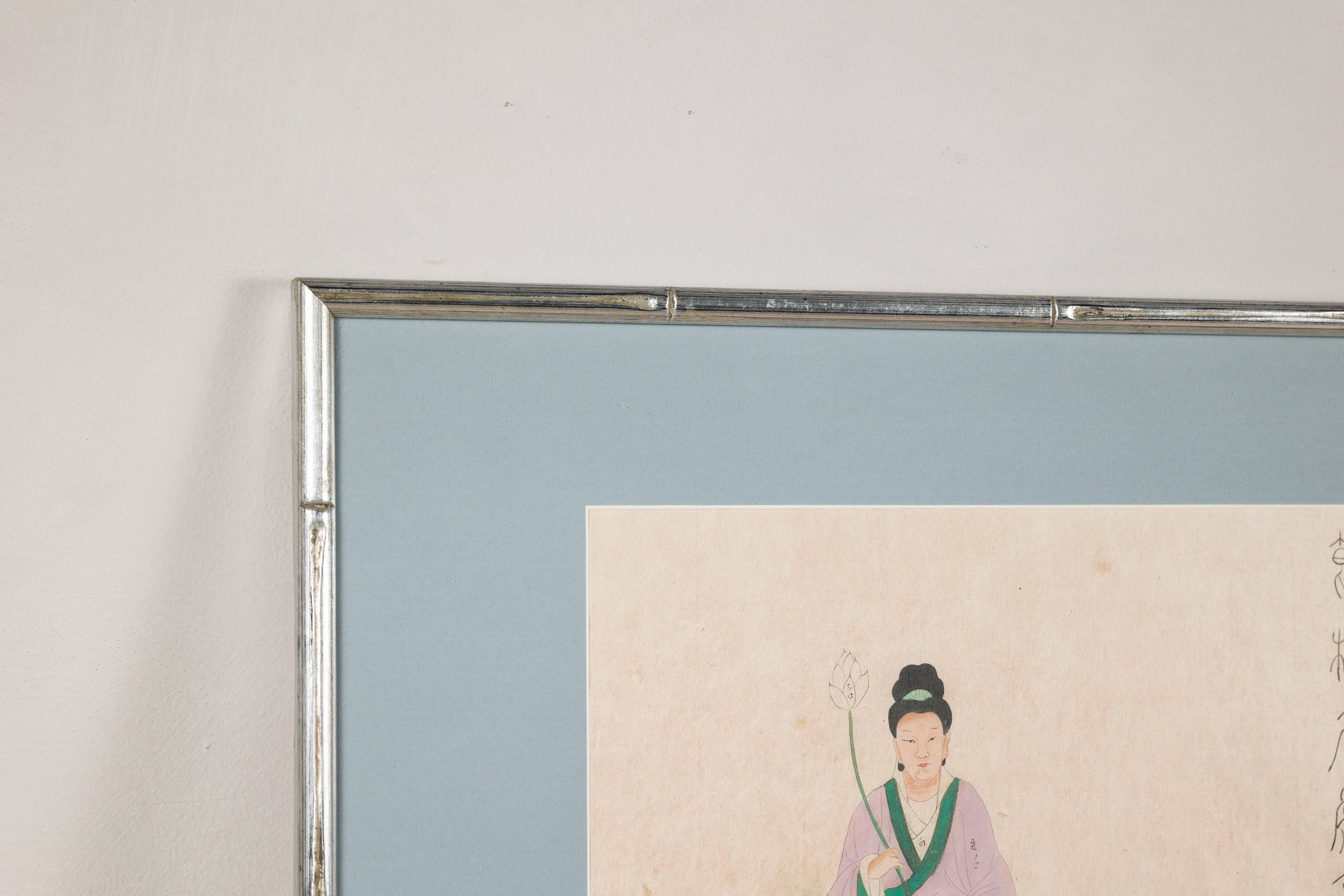 Close-up of the silvered frame and pale blue mat around a Japanese print