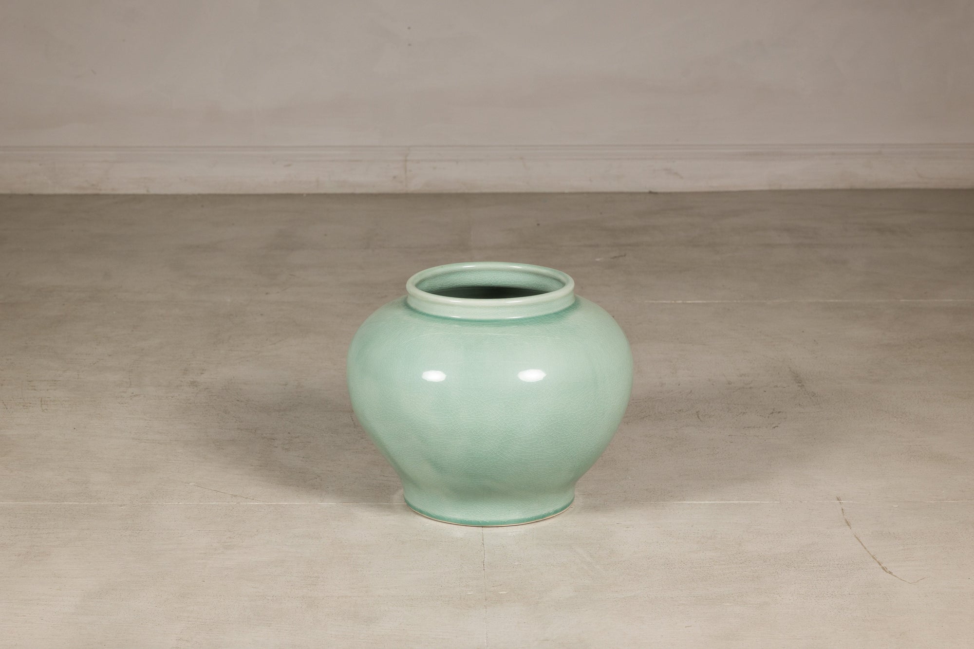 Celadon ginger jar form vase shown at smaller scale in a studio setting