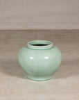 Celadon ginger jar form vase shown at smaller scale in a studio setting