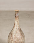 Cream and brown drip-glazed ceramic bottle vase with narrow neck, close-up against a light background.