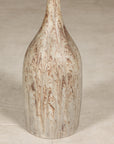 Close-up of tall cream and brown drip-glazed ceramic bottle vase with narrow neck and textured hand-finished surface.