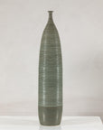 Green-glazed ribbed ceramic vase on a white table.