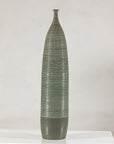 Tall green-glazed ribbed ceramic vase on a white table.