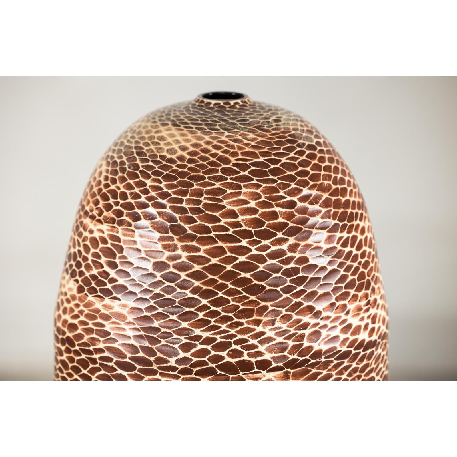Neutral-tone ceramic vase with snakeskin textured glaze, close-up against a plain background.