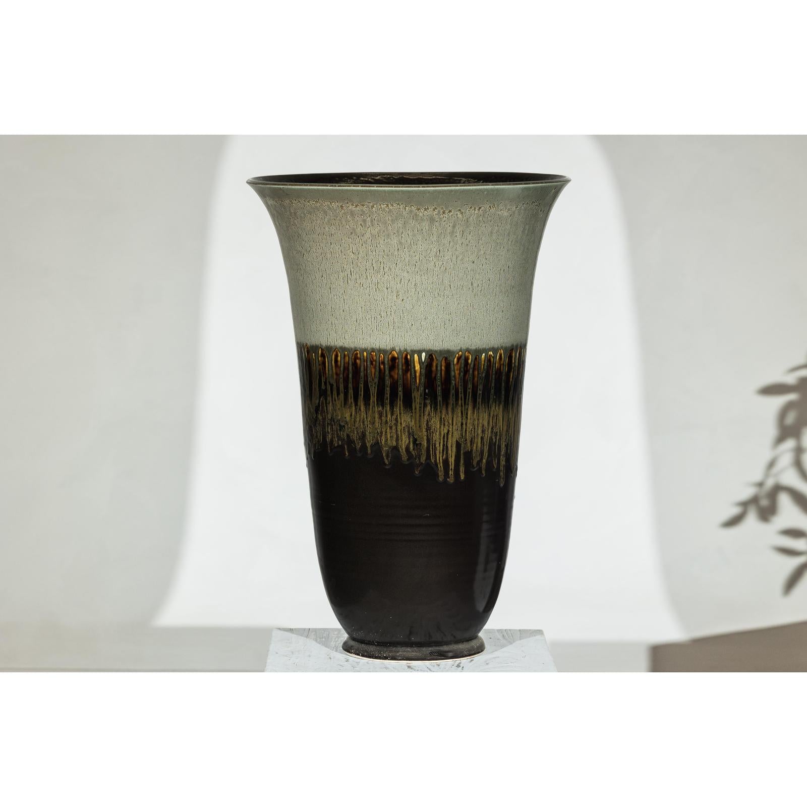 Close-up of large green-grey and brown drip-glazed ceramic planter with flared rim and artisan details.