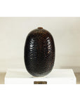 Deep brown and black ceramic vase with honeycomb texture on a white platform against a plain background.