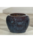 Close-up of vintage blue and aqua glazed ceramic planters on a light floor against a white wall.