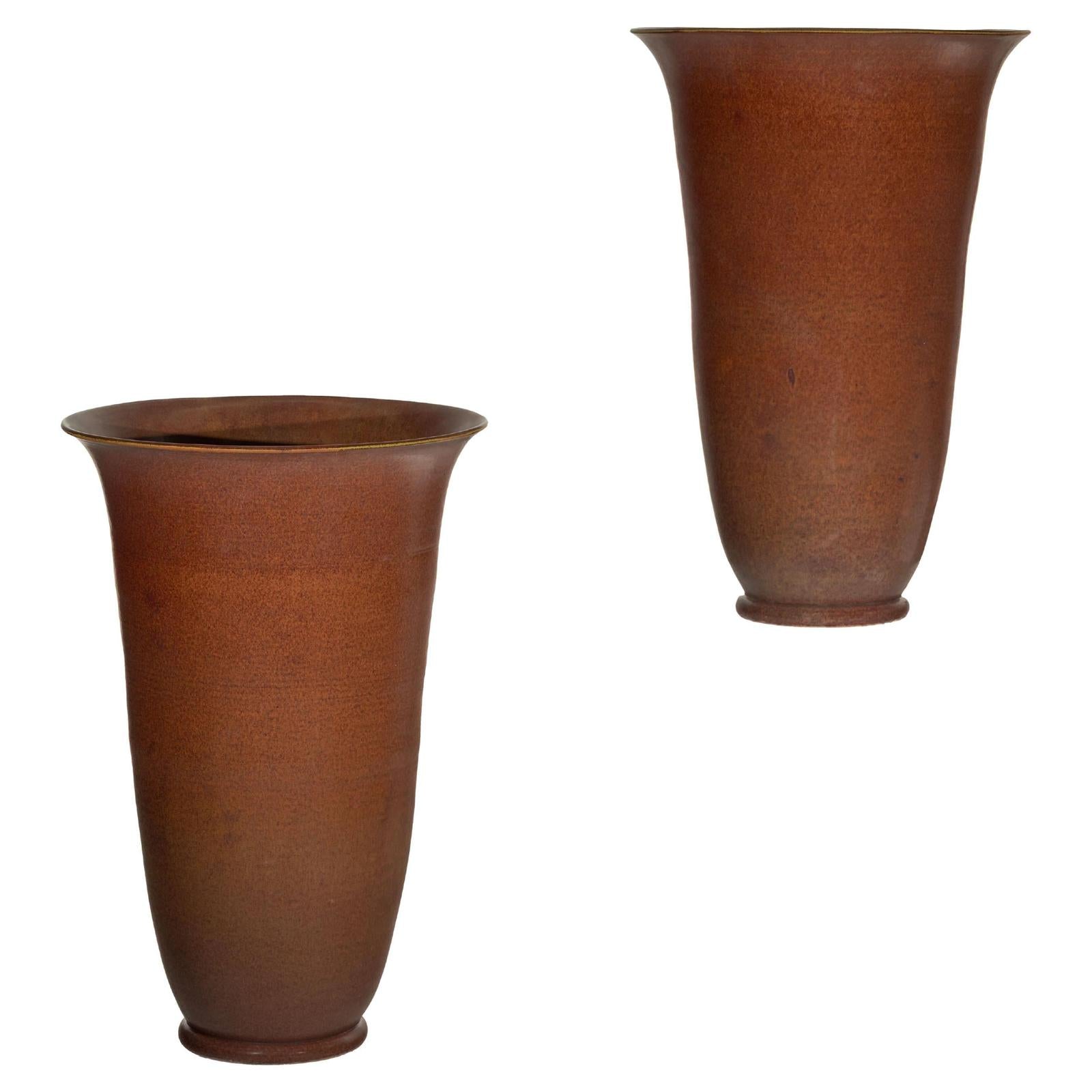 Brown ceramic vases with subtle red undertones, pair set against a plain white background, close-up view.