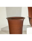 Brown ceramic vases with red undertones next to a white pedestal, close-up.