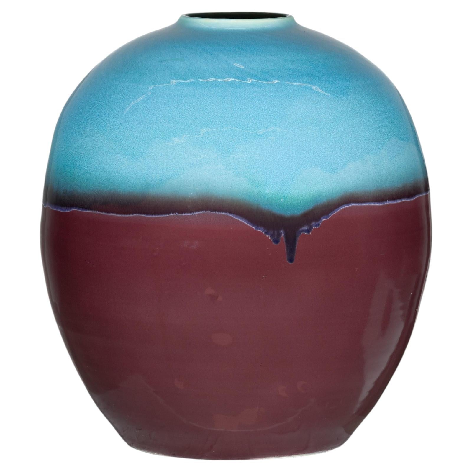 Close-up of round ceramic vase with turquoise glazed top, brown bottom, and small opening, modern style.