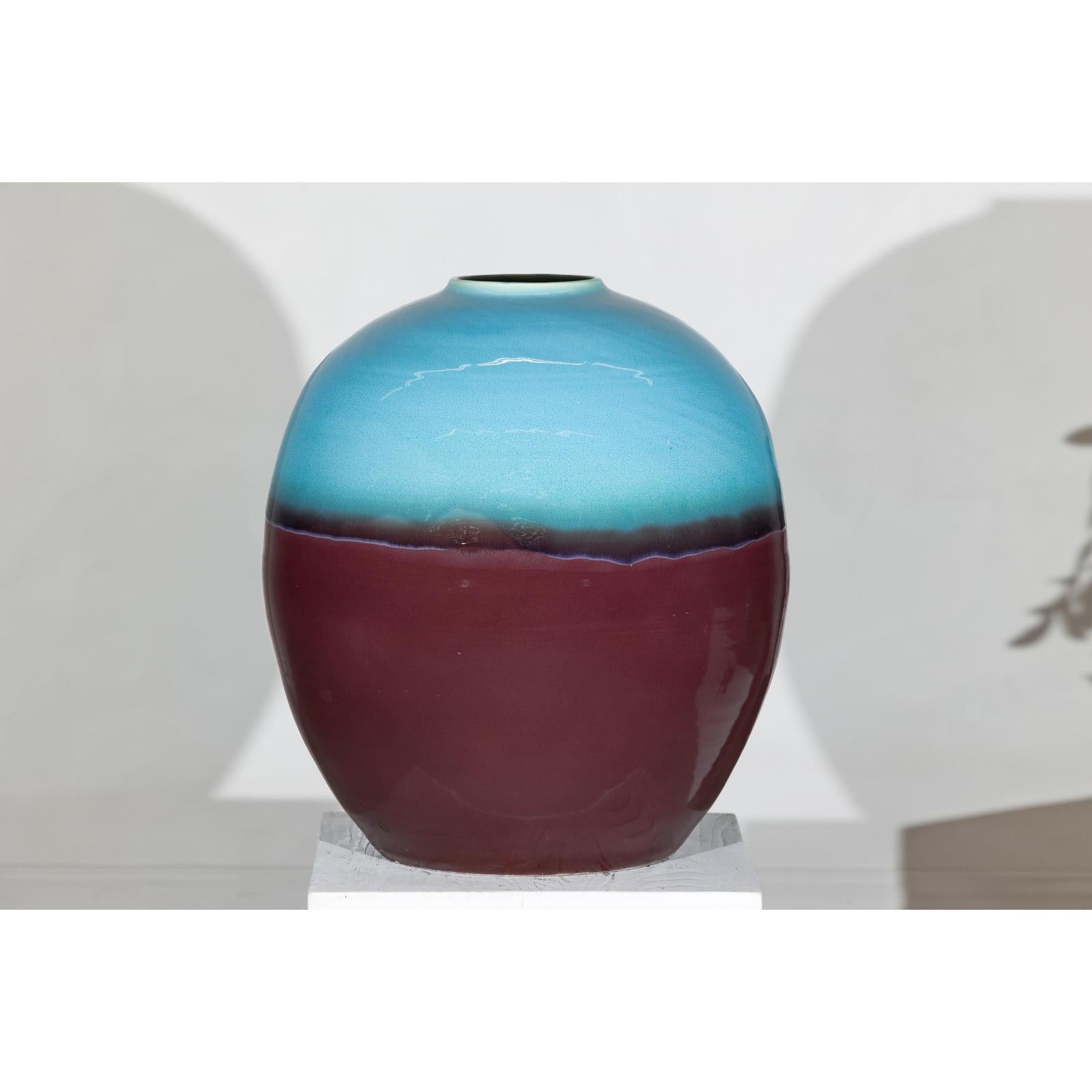 Turquoise and brown ceramic vase on white pedestal.