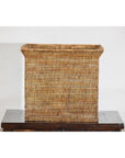 Square vintage rattan storage box with side handles on dark wood table, white background.