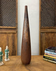 Brown and copper textured ceramic vase on a table with two figurines and books.