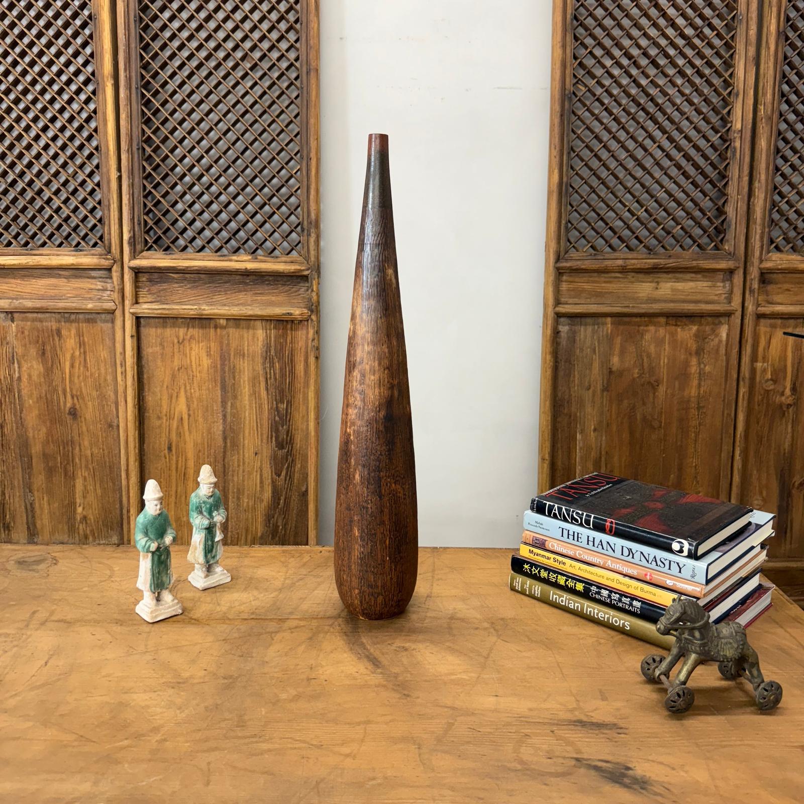 Brown and copper textured ceramic vase on wooden table with books, statues, and a horse.