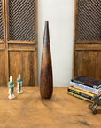 Brown and copper textured ceramic vase on wooden table with books, statues, and a horse.
