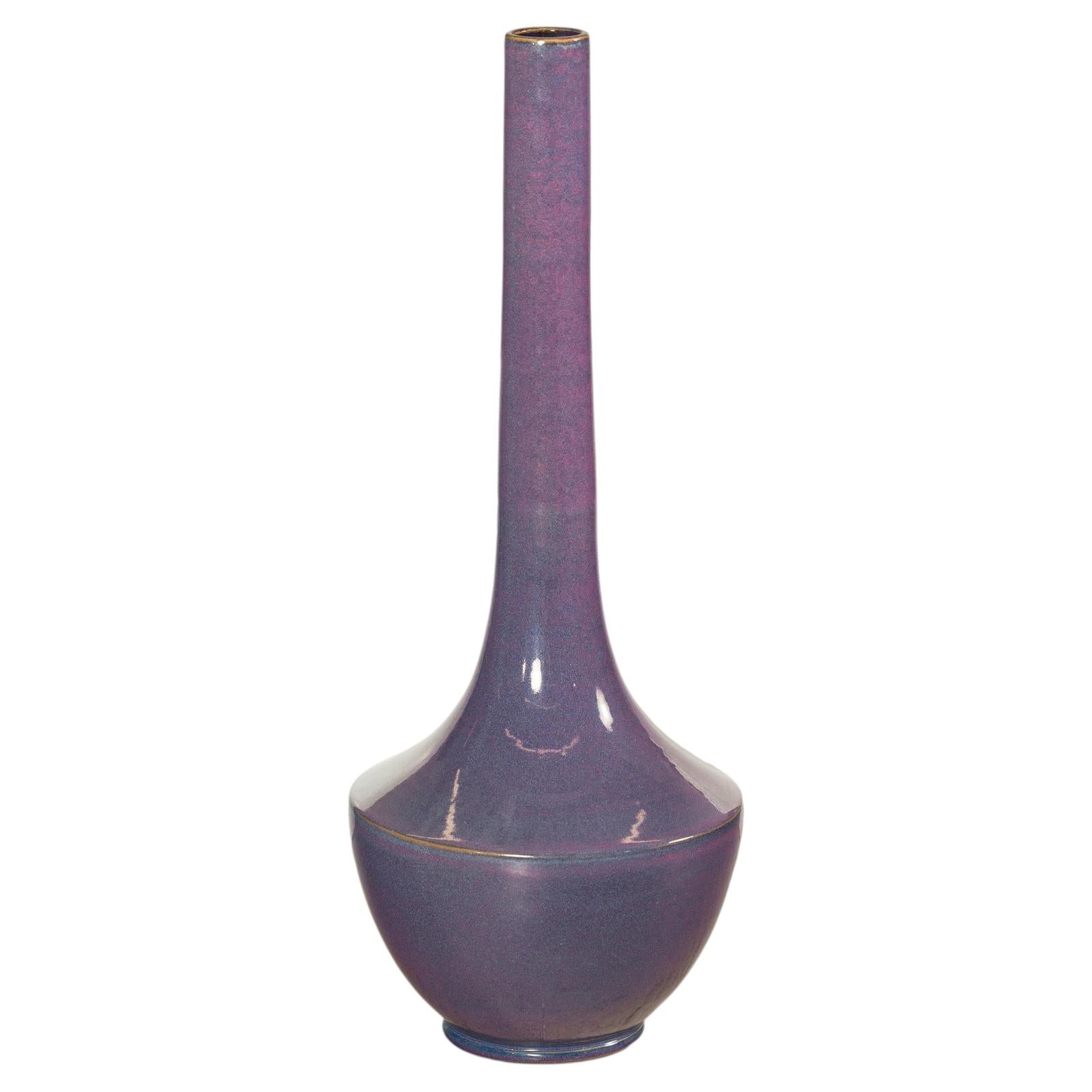 Purple ceramic vase with tall slender neck and glossy finish, sculptural decor on white background.