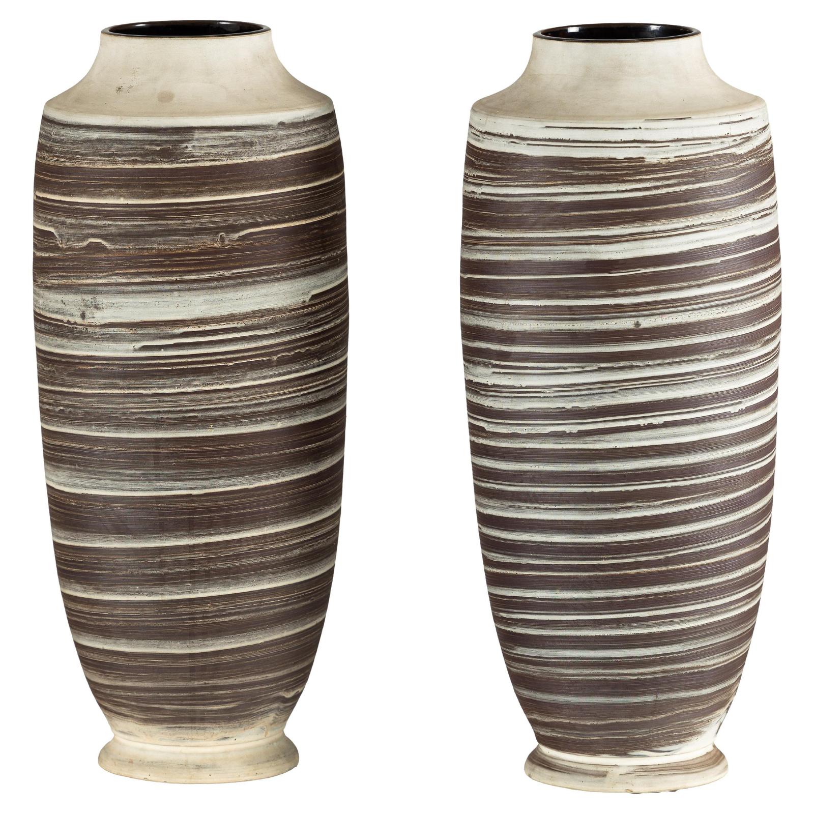 Brown and white ceramic vases with horizontal swirl design, hand-thrown, close-up on plain background.