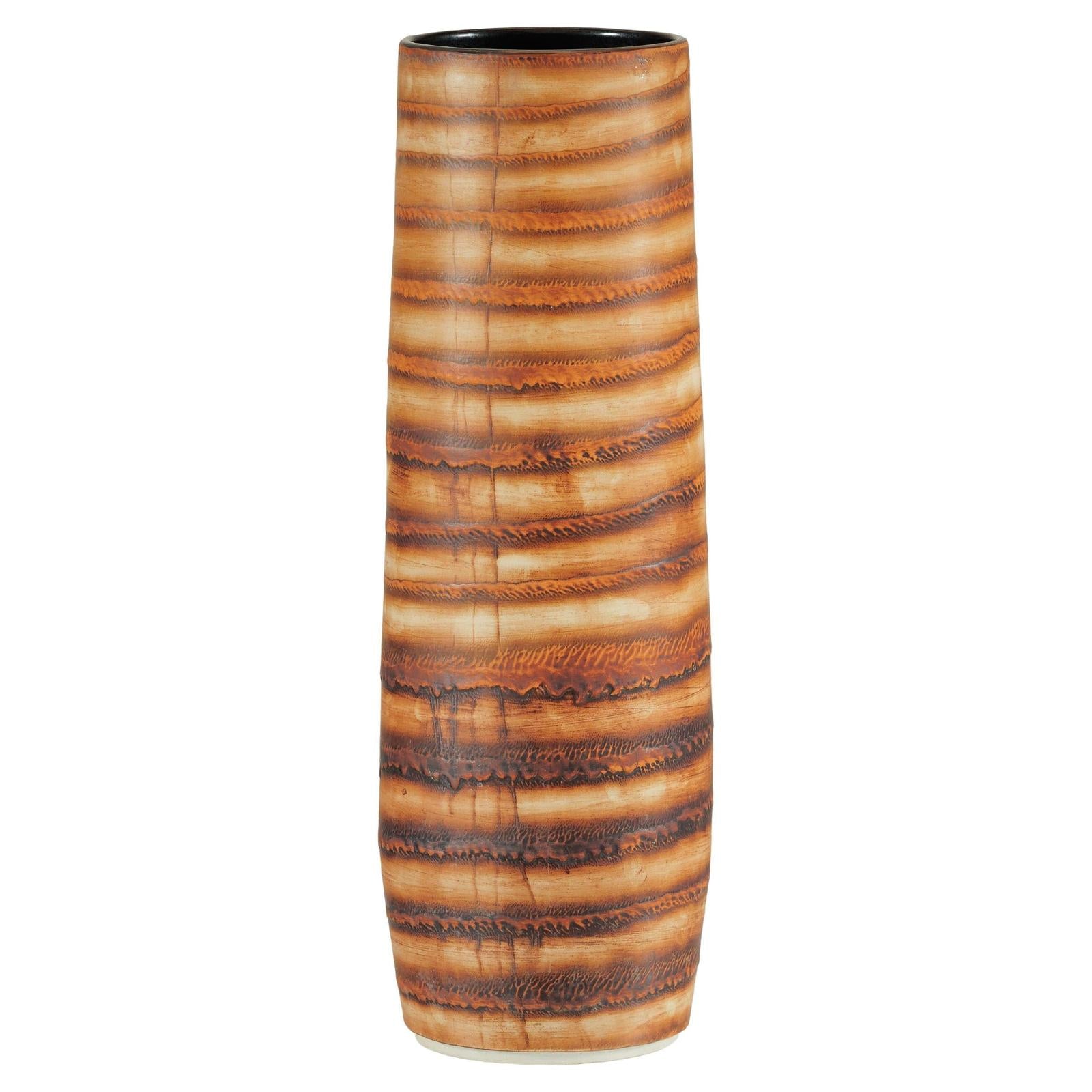 Close-up of tall orange-brown ceramic vase with swirl design and glossy finish.