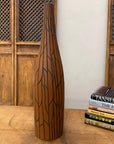 Sand brown orange ceramic vase with black crackle design beside stacked books on a wooden table.