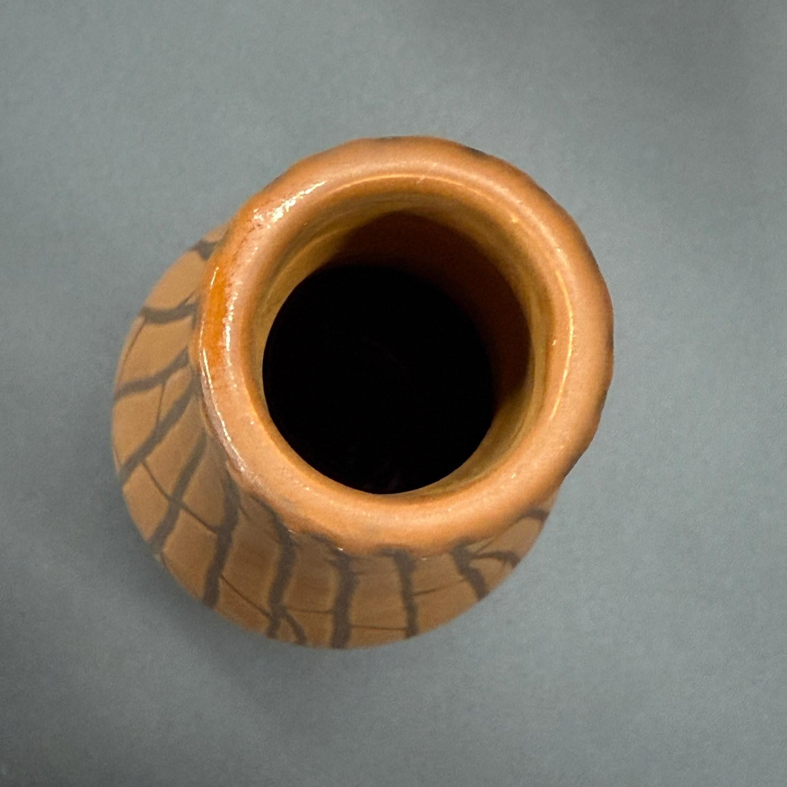 Sand brown and orange ceramic vase with black crackle design, viewed from above.