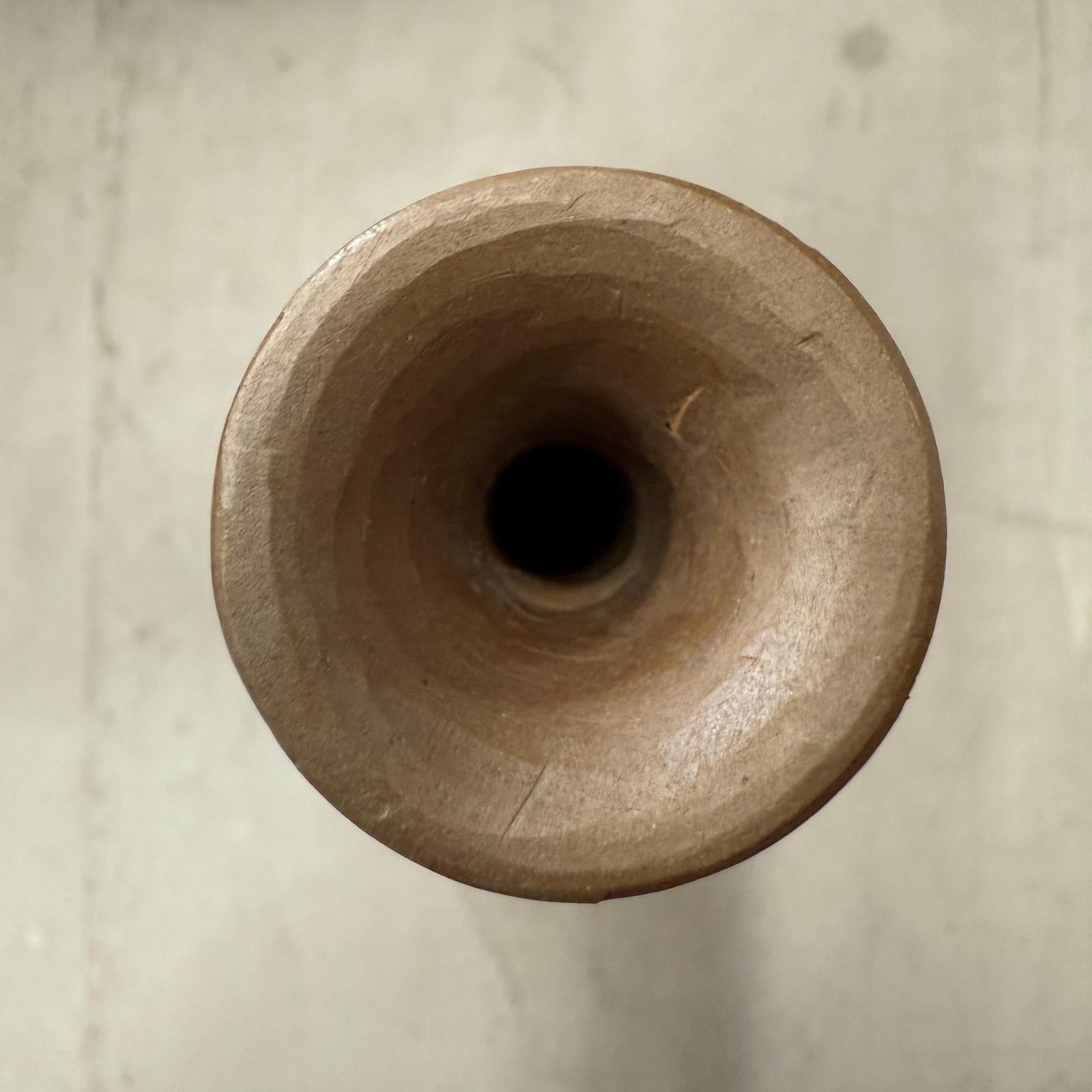 Top view of orange wooden vase with black swirl, hollow cylinder and smooth opening.