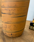 Close-up of an orange vase with black swirl, ceramic, beside stacked books on a wooden surface.