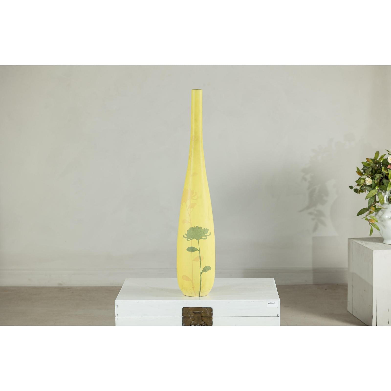 Yellow ceramic vase with hand-painted flowers, tall and skinny, displayed on a white box against a plain background.