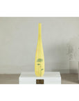 Yellow ceramic vase with hand-painted flowers, tall and skinny, displayed on a white box against a plain background.